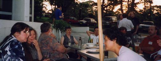 People talking around a outdoors table prior to the conference dinner.