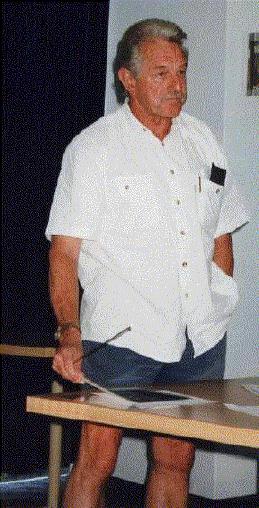 Professor Brian Gray, hand in pocket, states at the audience: 11th February 1999