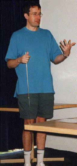 John Billingham. Pointer pointing down, moves his left hand in a meaningful manner.